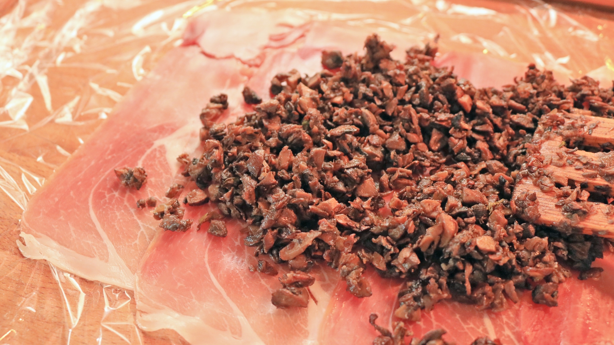 Spreading duxelles on a sheet of prosciutto