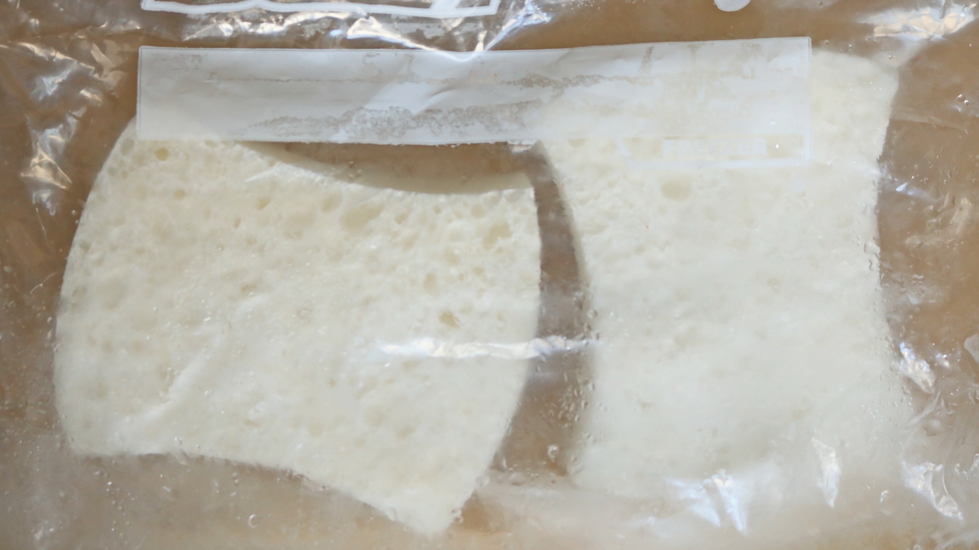 Two frozen white sponges in a plastic freezer bag.