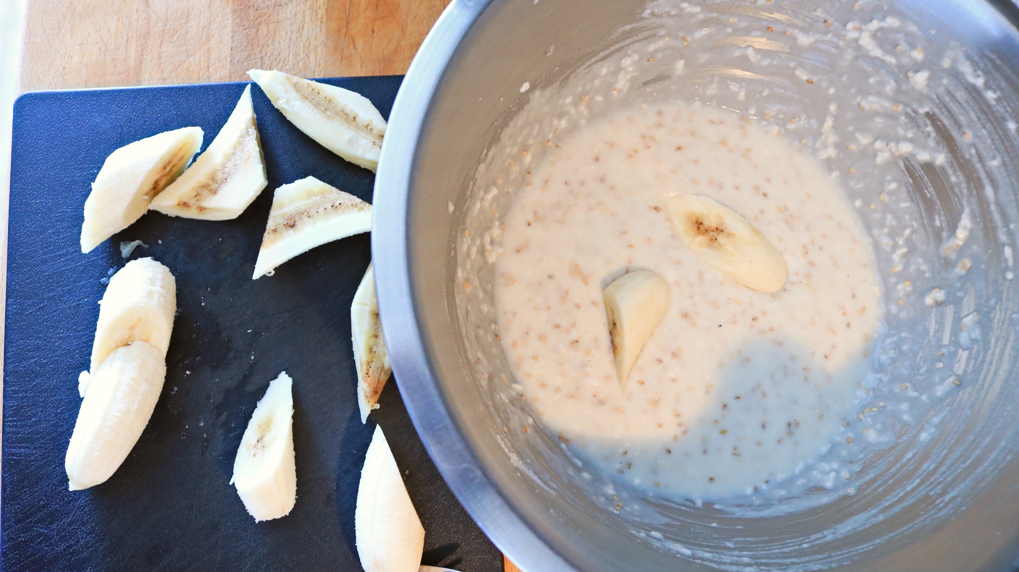 Sliced bananas next to a bowl of batter.