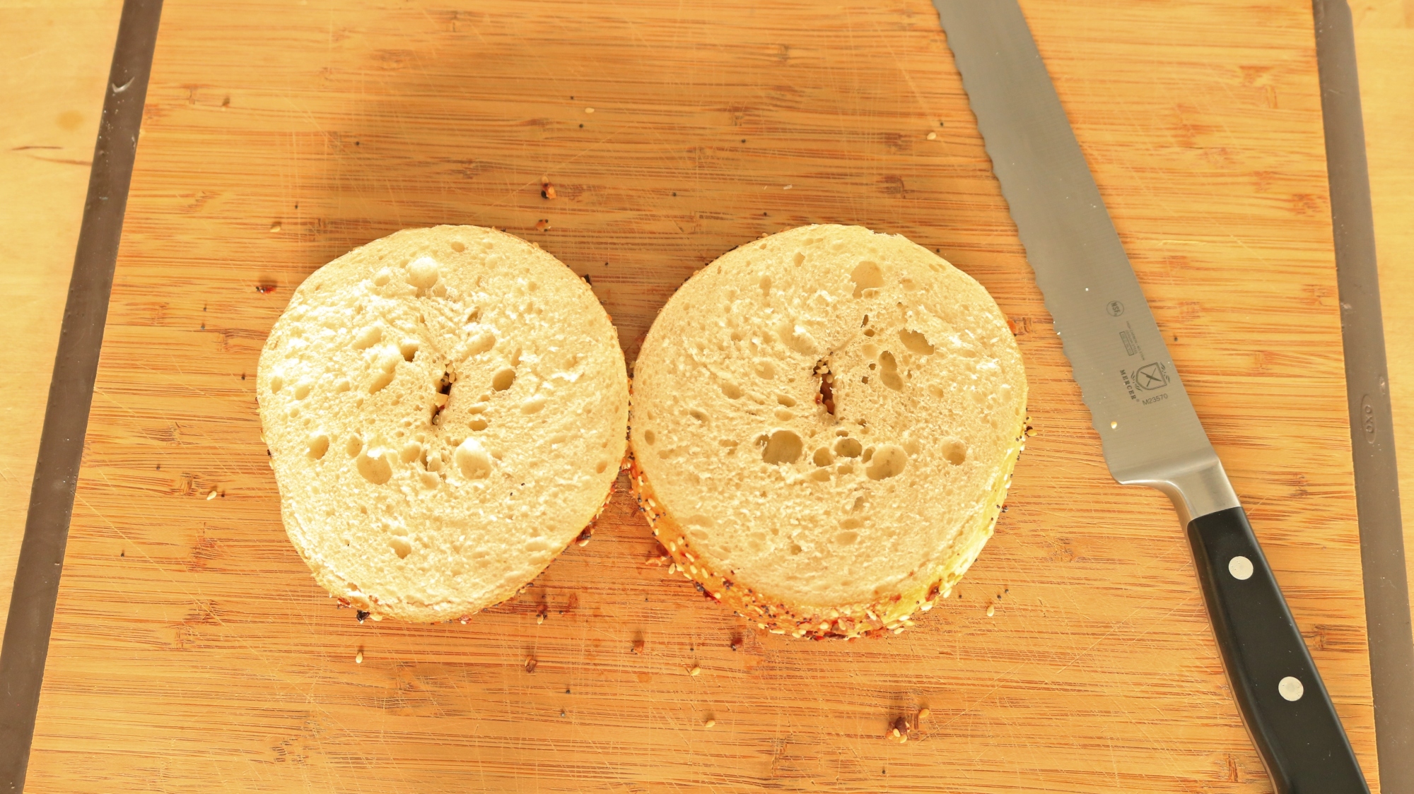 Two bagel halves open on a cutting board.