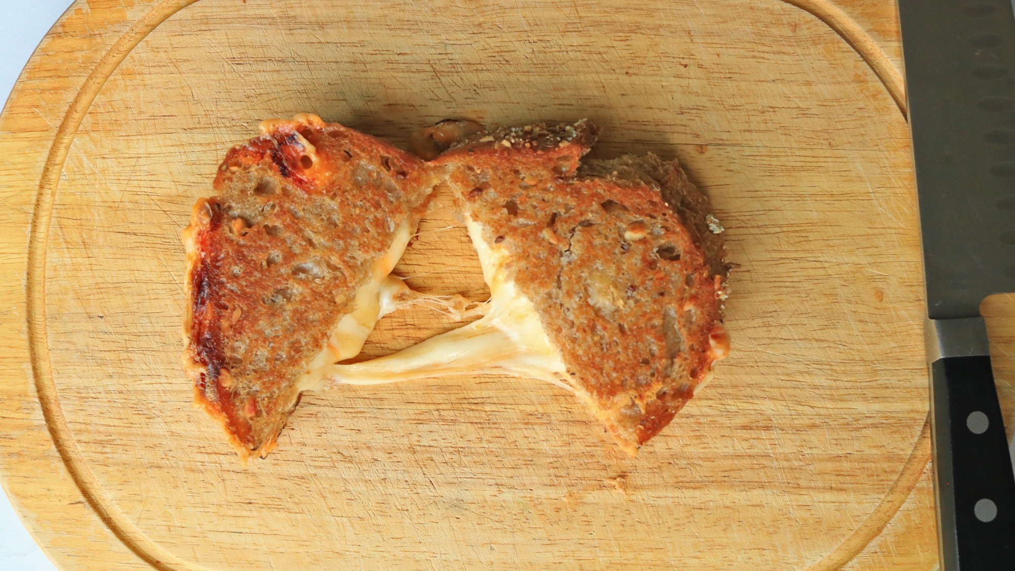 Grilled cheese cut in half on a cutting board.