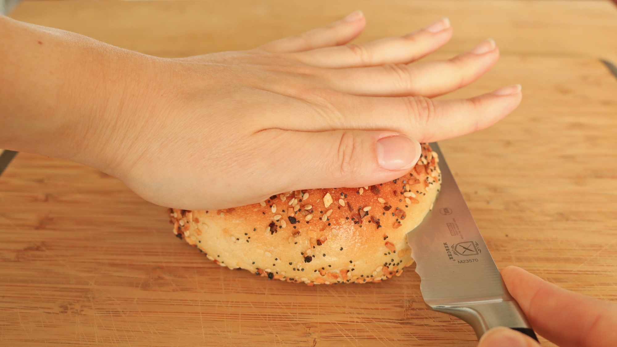 Knife sawing into a bagel