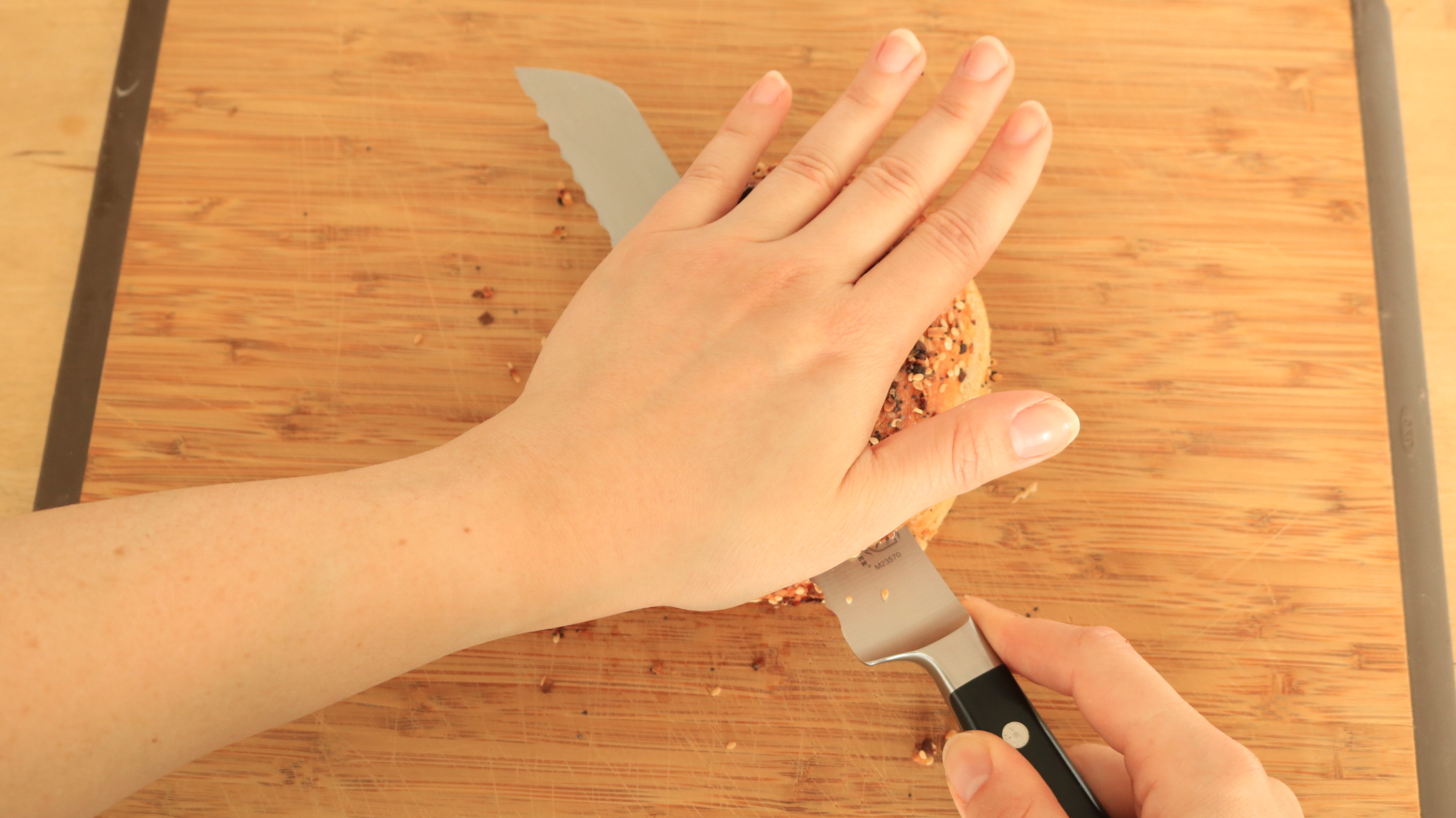 Hands slicing a bagel.